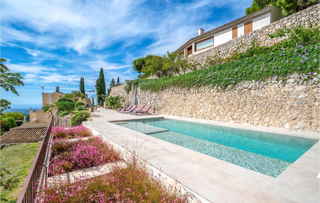 una casa con piscina junto a una pared de piedra en Awesome Home In Puigpunyent With Outdoor Swimming Pool And 3 Bedrooms, en Puigpunyent