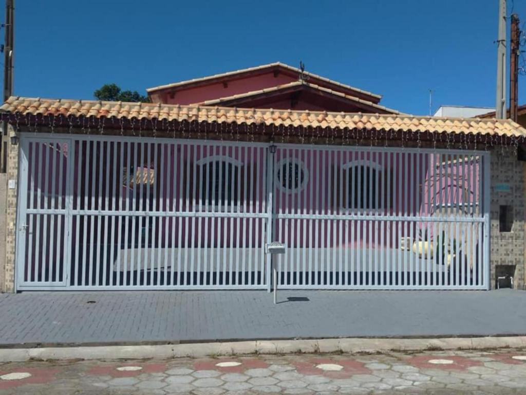 a white fence in front of a house at Casa Rosa de Peruíbe - Casa de Temporada 3 dormitórios, 10 hóspedes, piscina, wi-fi, netflix, 800 metros da praia in Peruíbe