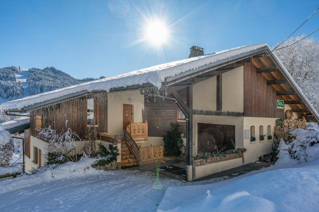 une maison recouverte de neige avec le soleil derrière elle dans l'établissement Chalet Rochebrune - Apartment Les Chavannes, aux Gets