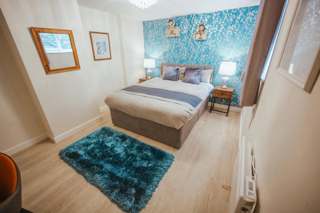 a bedroom with a bed and a blue wall at KENDAL HOLIDAY FLATS in Kendal