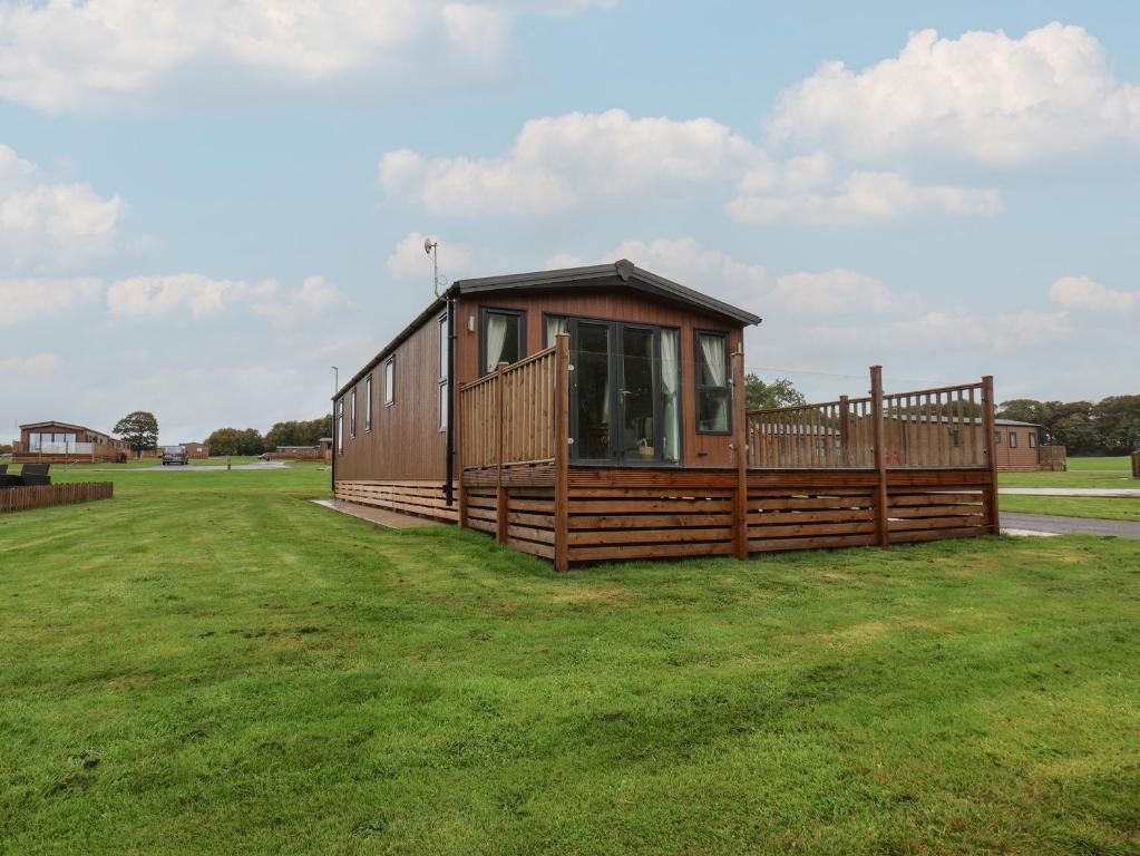 a large wooden cabin in a grass field at Woody Ray in Bridlington