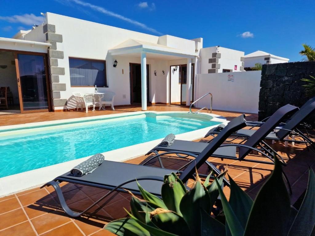 une villa avec une piscine et quelques chaises dans l'établissement Villa Lagarto heated pool aircon central Playa Blanca, à Playa Blanca