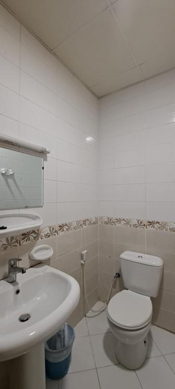 a bathroom with a white toilet and a sink at Private Room - Apartment in Al Ḩayrah