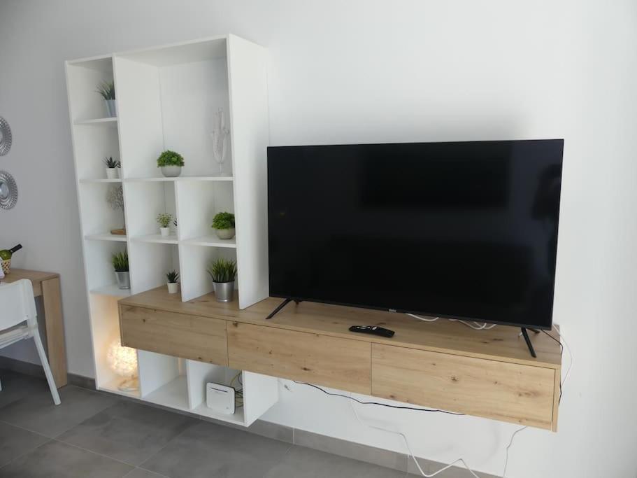 a flat screen tv on a wooden stand in a living room at 19 Piso céntrico, nuevo y bien equipado en La Trinidad in La Laguna