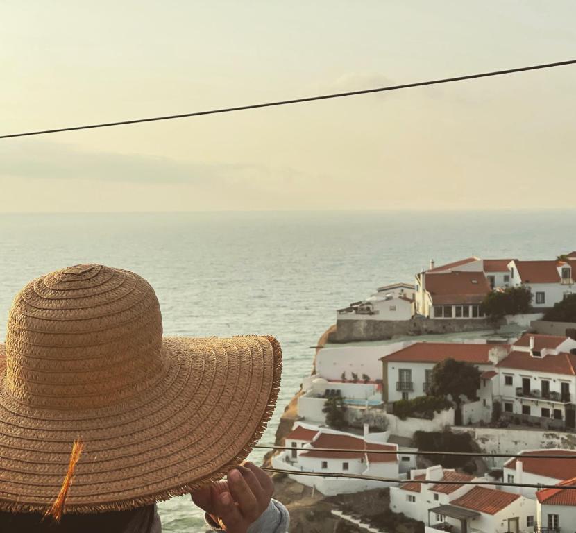 una persona con un cappello di paglia che guarda l'oceano di Azenhas do Mar Cliffs House a Sintra