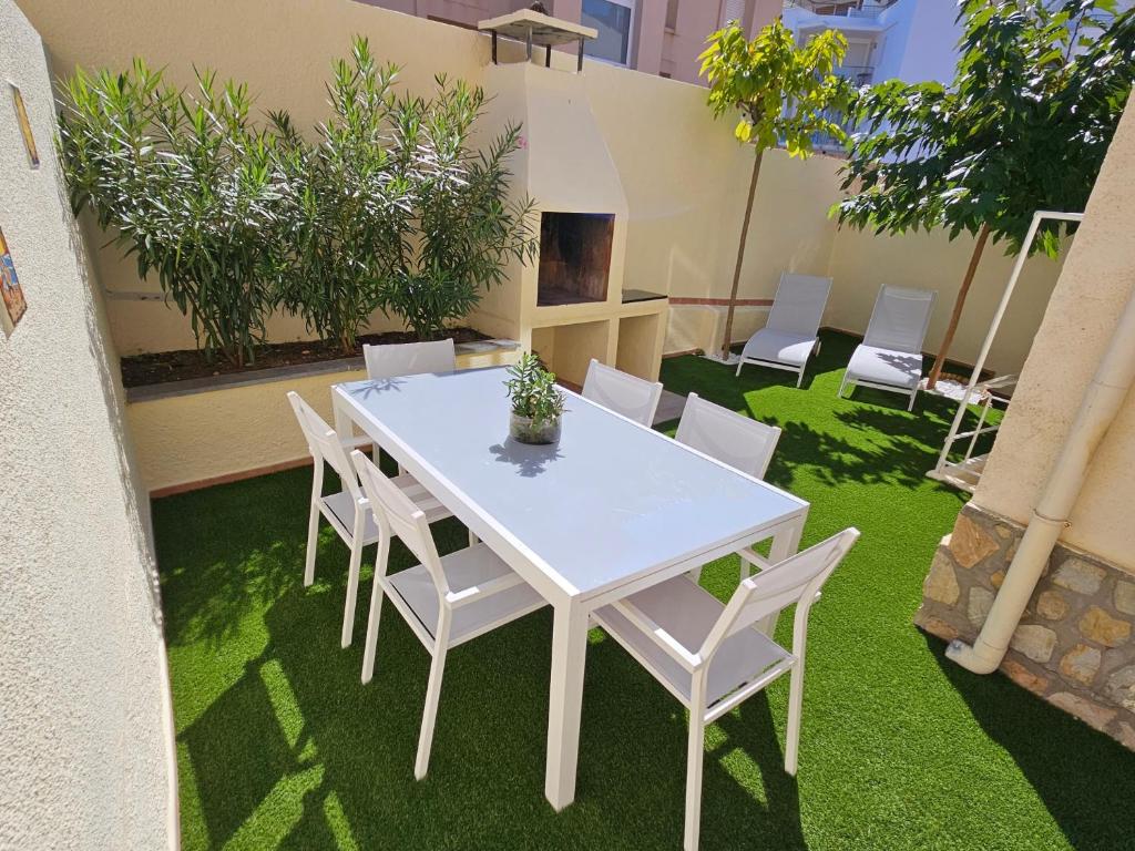 a white table and chairs on a patio with grass at Casa Sebastian in L'Escala