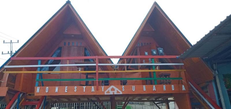 ein Gebäude mit spitzen Dächern und einem Schild darauf in der Unterkunft Homestay Subarda Kamar Natural in Solok