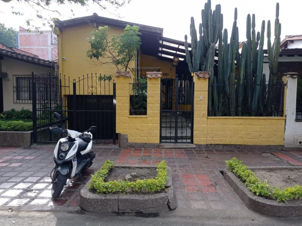 a motorcycle parked in front of a house with a fence at Yellow House Hostel in Medellín