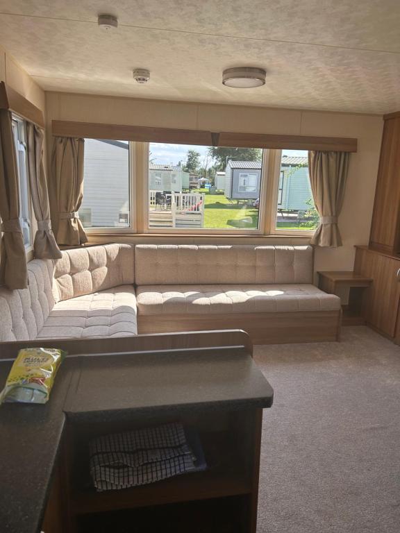 a living room with a couch and a large window at Parkdean cherry tree holiday park Burgh castle Great Yarmouth in Belton