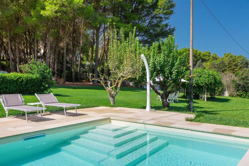 - une piscine avec 2 chaises à côté d'une cour dans l'établissement Residenza del Timo, à Gallipoli