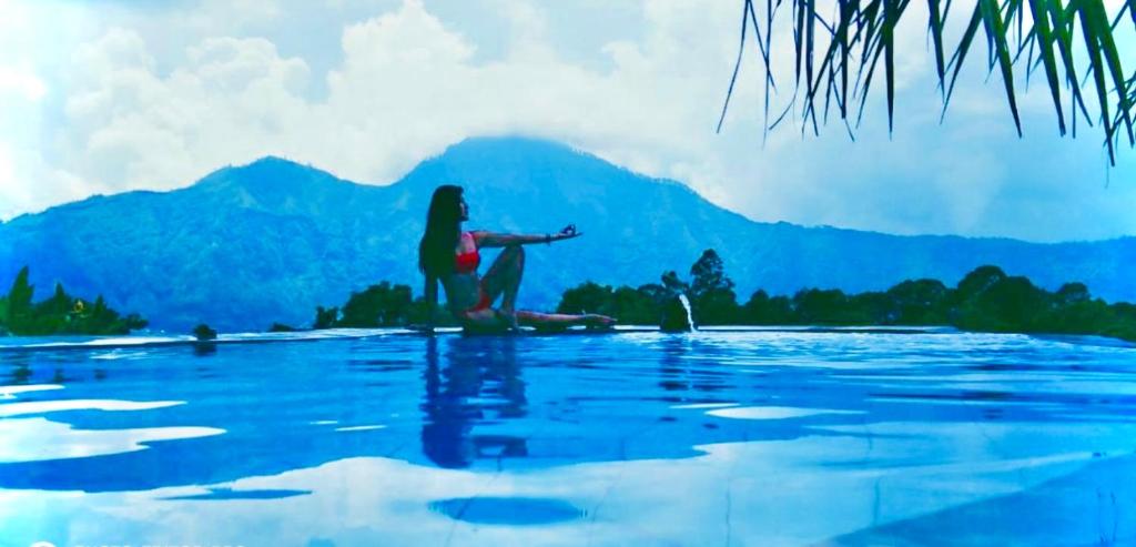 a woman sitting on the edge of a body of water at Batur Volcano Guesthouse in Kintamani