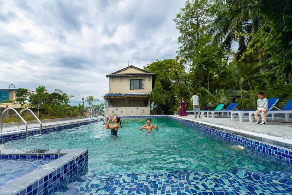 un gruppo di persone che nuotano in piscina di Hotel Parkside & Swimming Pool-Between Greenery and Azure ,Your Perfect Retreat a Chitwan