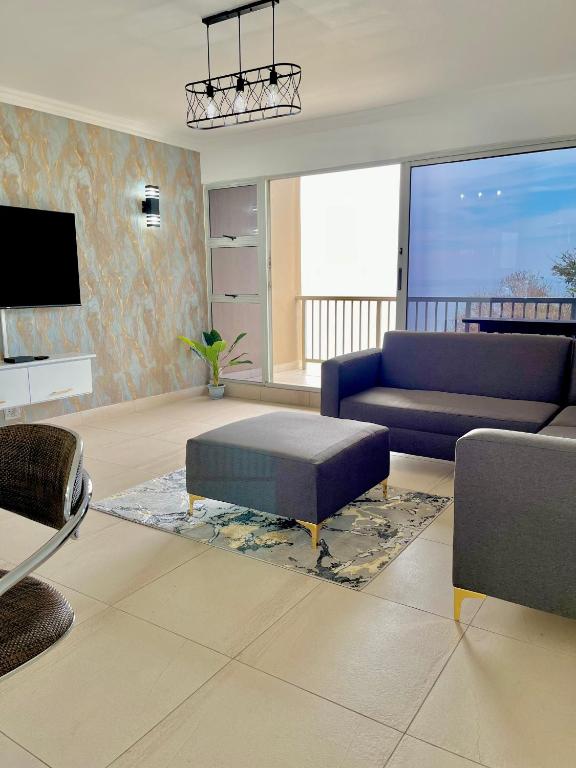 a living room with a blue couch and a tv at 101 Camarque - 3 Bedroom Beachfront Apartment In Umdloti - 180 Degree Sea Views in Umdloti