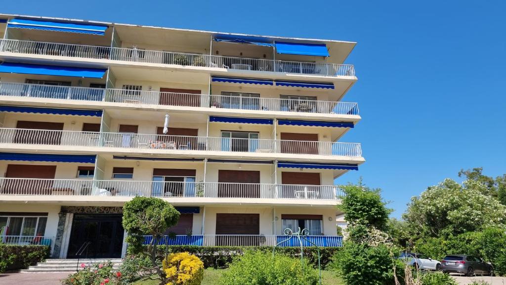 un immeuble avec des balcons bleus et des arbres dans l'établissement Studio plage de sable, à Antibes