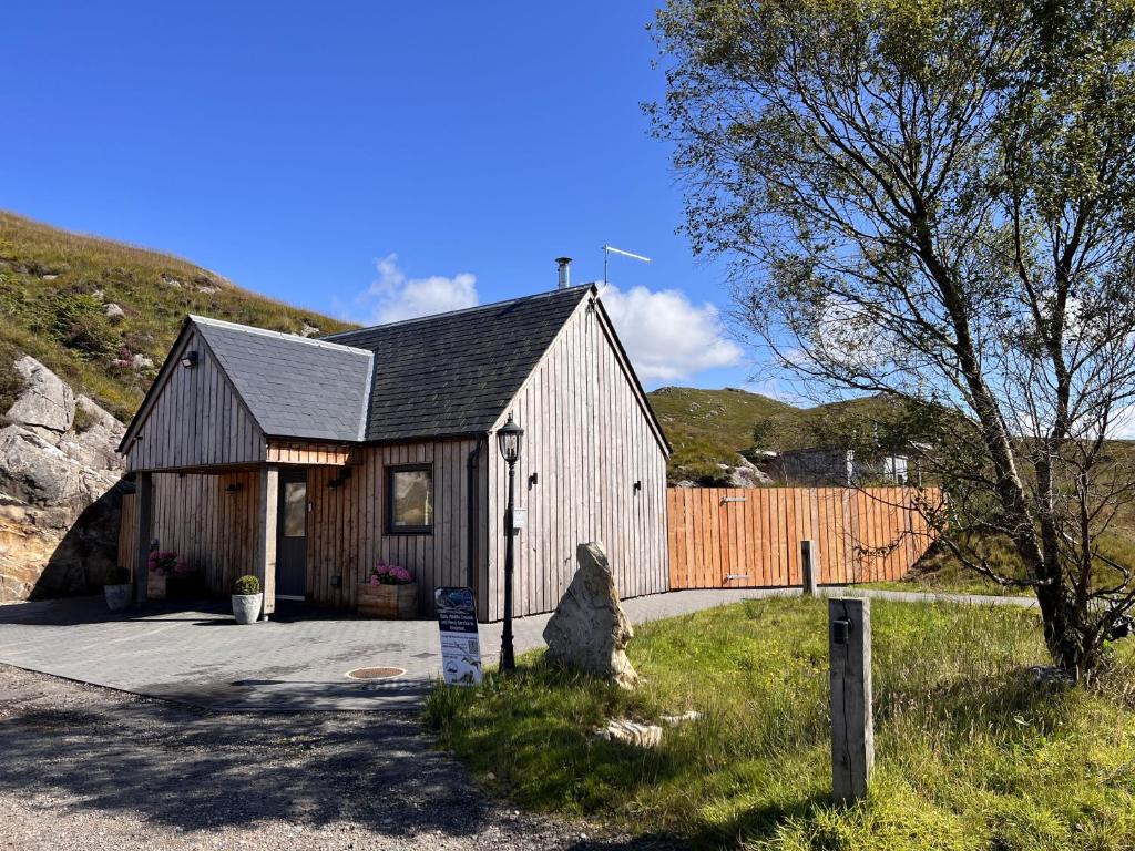 um celeiro com um cão sentado fora dele em Raasay Studio Lodge em Arisaig