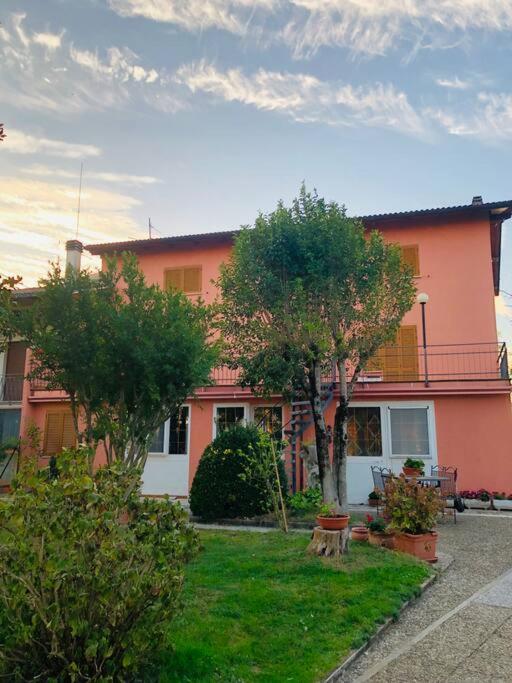 uma casa cor-de-rosa com árvores à frente. em Villa Fiorella em Costacciaro