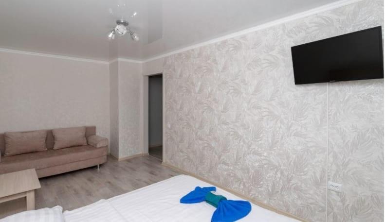 a bedroom with a couch and a television on a wall at Торонто in Petropavlovsk