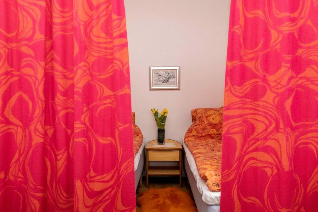 ein Schlafzimmer mit roten Vorhängen und einem Bett und einer Vase aus Blumen in der Unterkunft Hot spot of Vaasa with City Hall views in Vaasa