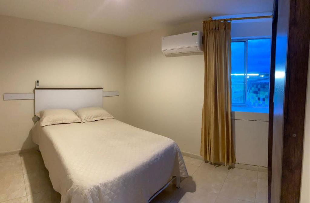 una camera con un letto bianco e una finestra di Valledupar I amplio y comodo apartamento cerca a todo y en zona segura de la ciudad a Valledupar