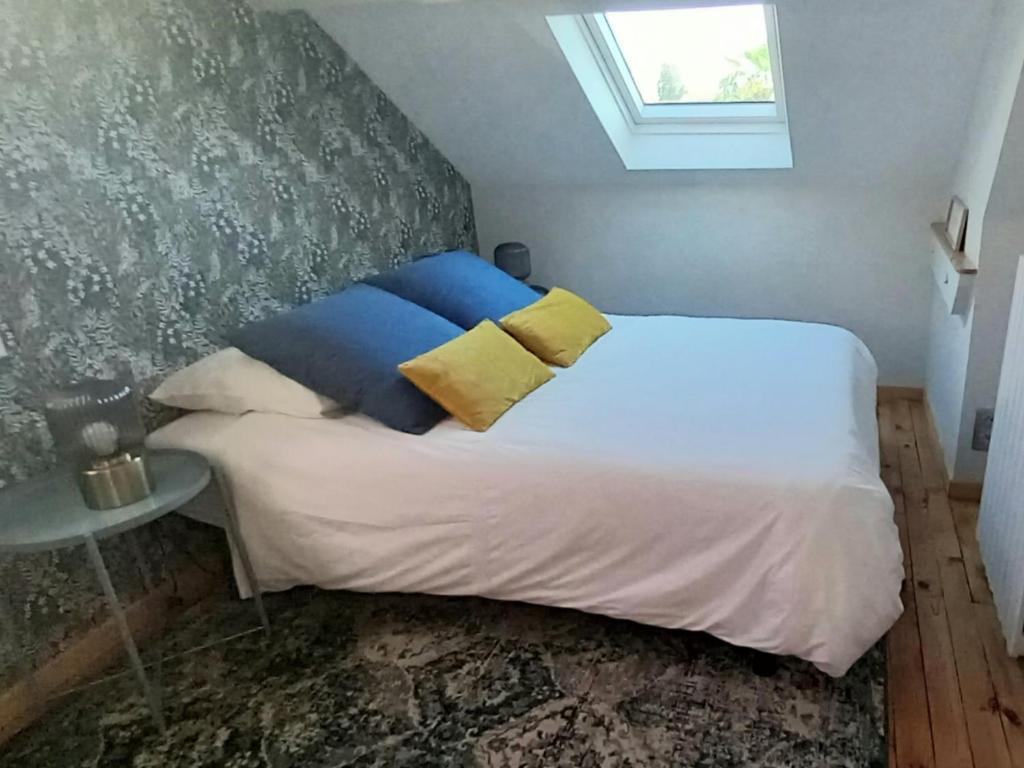 1 dormitorio con 1 cama con almohadas azules y amarillas en La Maison de Sylvie, chambres d'hôtes à Tarbes en Tarbes
