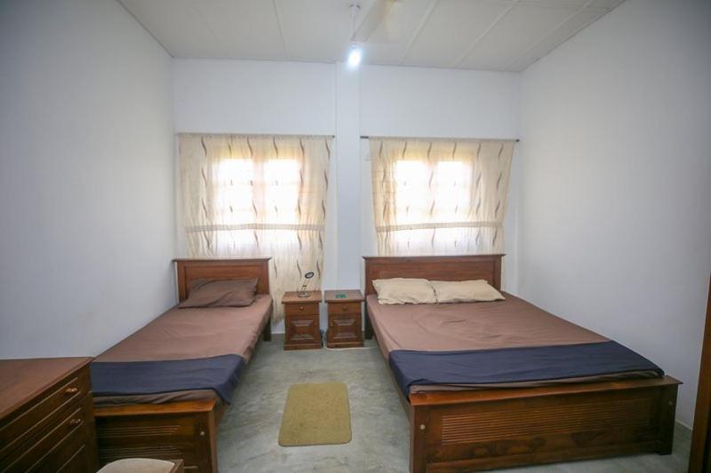 two beds in a room with two windows at Donkey clinic and education center in Mannar