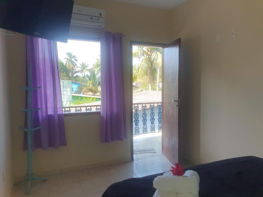 a bedroom with purple curtains and a large window at Pousada Cavalo Marinho Anexo in Abraão