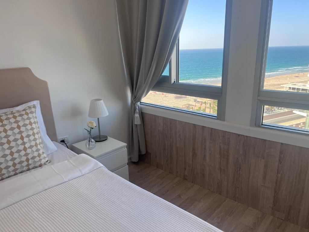a bedroom with a bed with a view of the ocean at Apartments 1126 Colony Beach with Pool Bat Yam Tel Aviv in Bat Yam