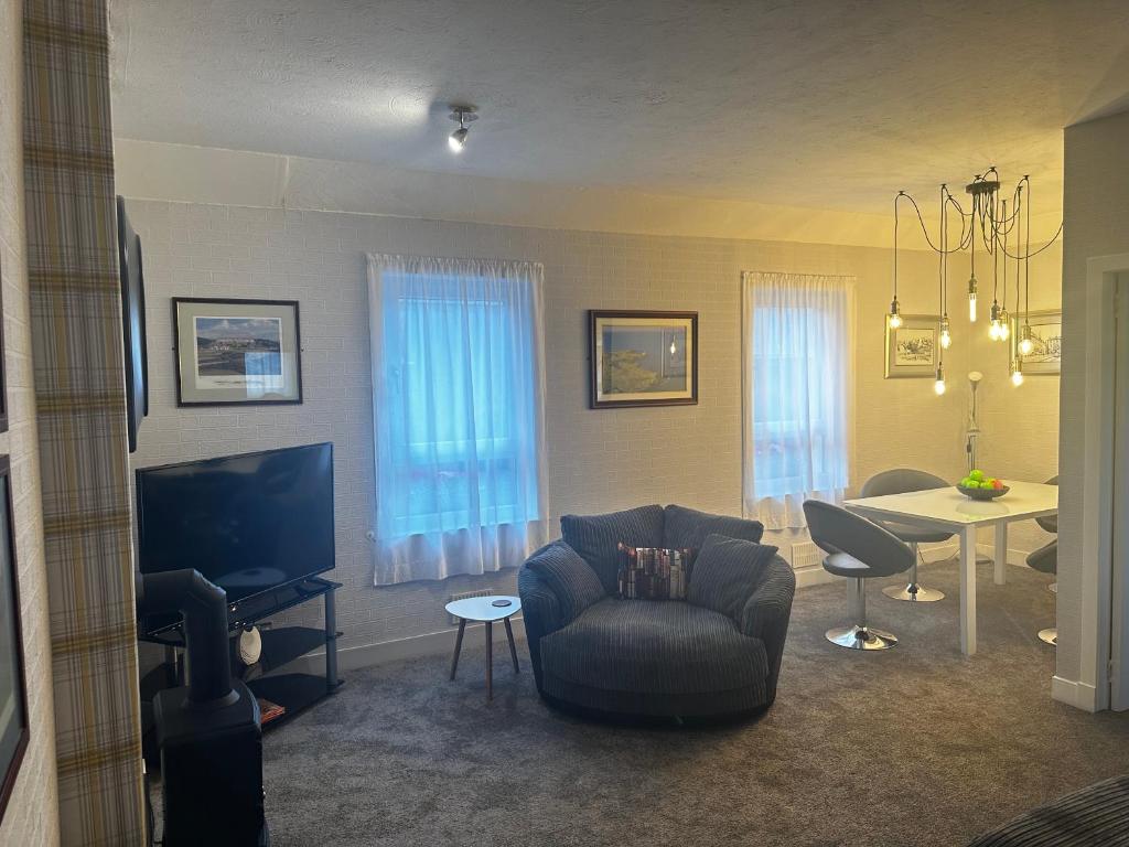 a living room with a chair and a tv and a table at The Sandgate New Immaculate 1-Bed Apartment in Ayr in Ayr