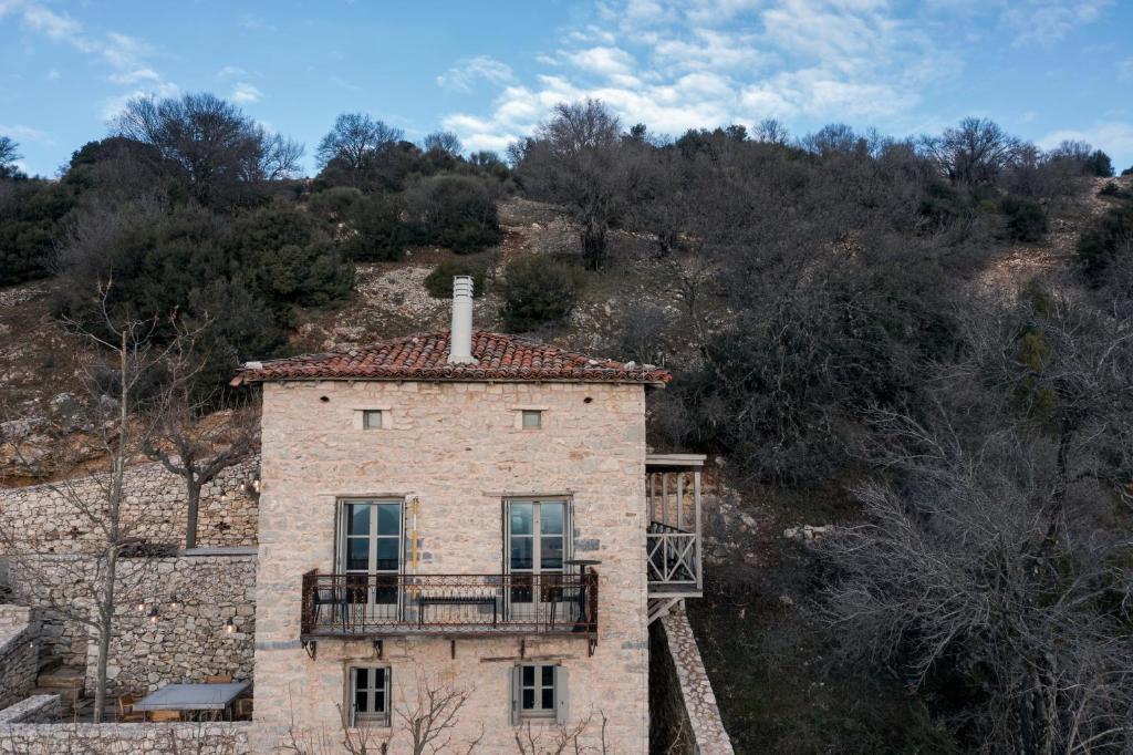an old stone house with a balcony on a hill at Moreas Peak Lodge in Magoúliana
