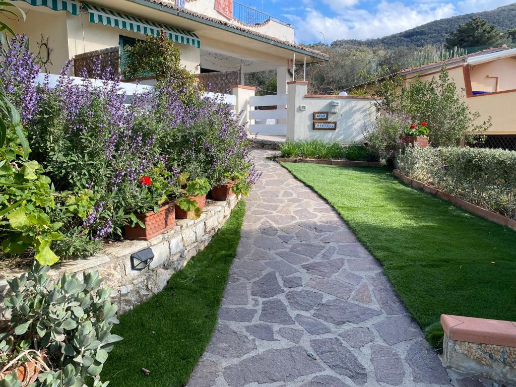 un jardin fleuri et un chemin en pierre dans l'établissement Beach apartments Isola d'Elba, à Portoferraio