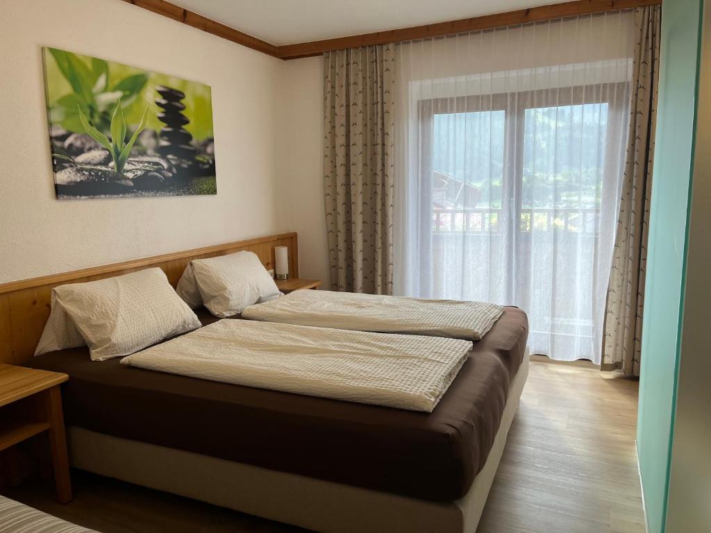 Bett in einem Zimmer mit einem großen Fenster in der Unterkunft Haus Amalie in Söll