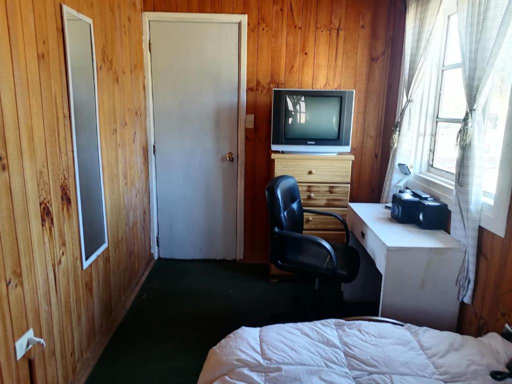 Habitación con escritorio, silla y TV. en Habitación individual el amenecer de la Estancia, en Isla Negra