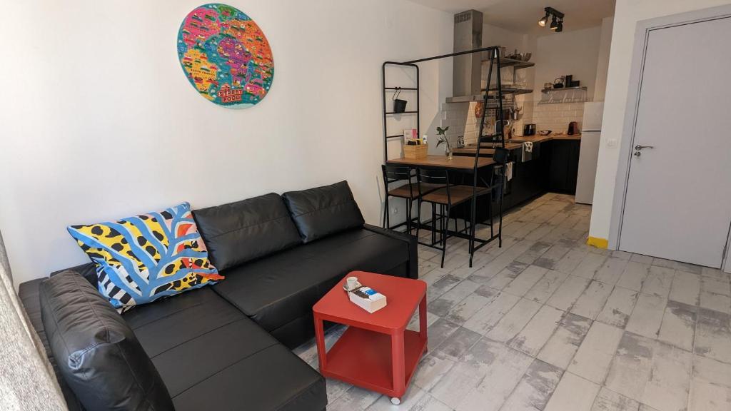 a living room with a black couch and a red stool at 65 Duck House in Sofia