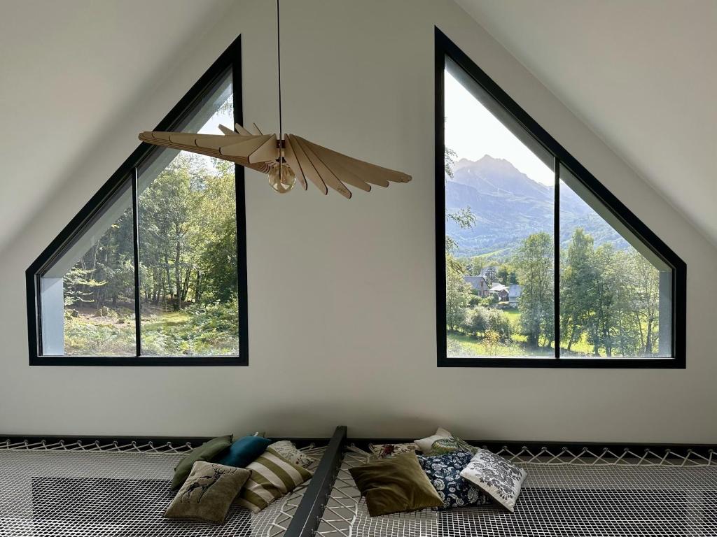 een kamer met 3 ramen en een bed met kussens bij L’Éterle, maison de montagne in Aucun