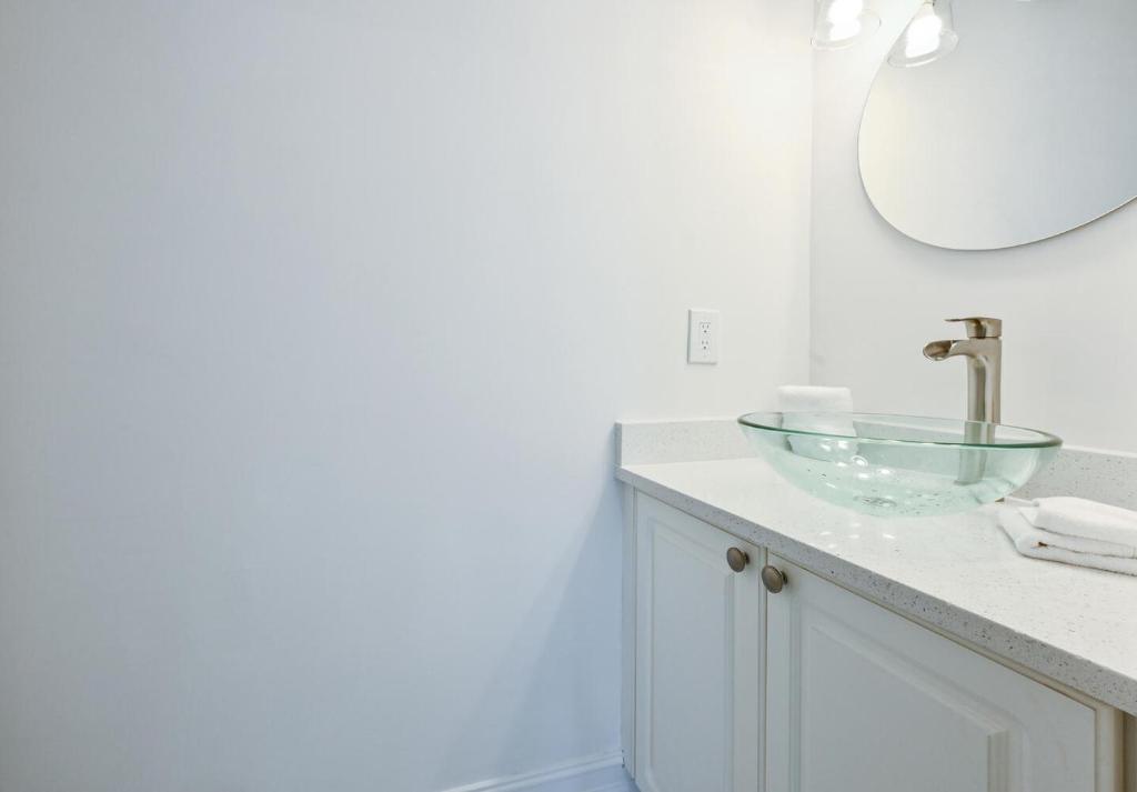ein Badezimmer mit einem Glaswaschbecken und einem Spiegel in der Unterkunft Spacious+Cozy Home, near the beach, heated pool. in Naples