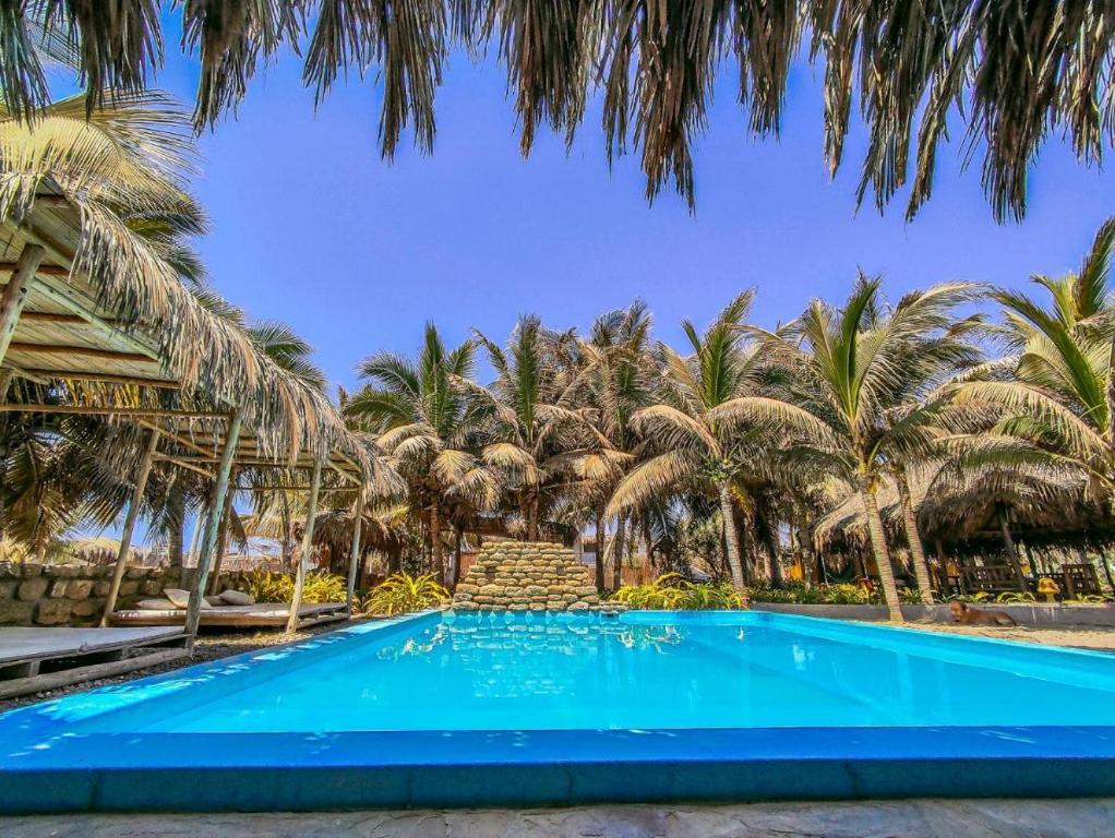 una piscina azul con palmeras en el fondo en La Casa de Sebas - Pool Beach Hotel Mancora, en Máncora