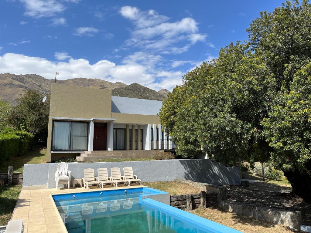 a house with a swimming pool and two lawn chairs at Andelka-Chumamaya Merlo San Luis in Merlo