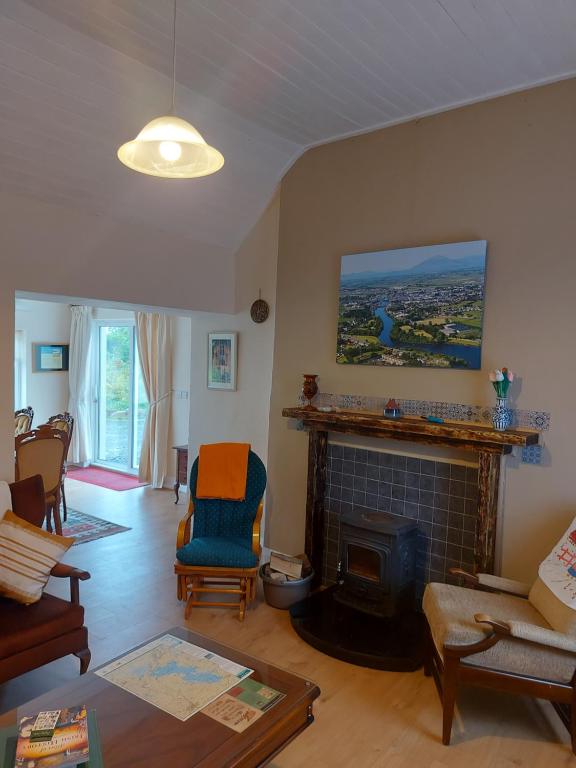a living room with a fireplace and a couch and chairs at Harmony Haven Cottage in Foxford