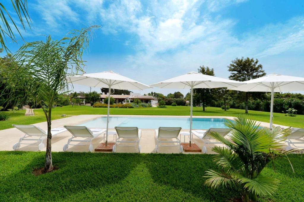 a swimming pool with chairs and umbrellas at Masseria San Rocco in Gallipoli