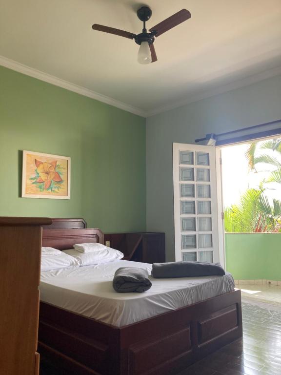 - une chambre avec un lit et un ventilateur de plafond dans l'établissement Casa em Aparecida, à Aparecida