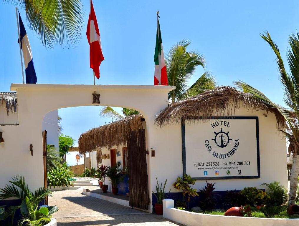 a building with two flags on top of it at Hotel Casa Mediterranea Mancora in Máncora