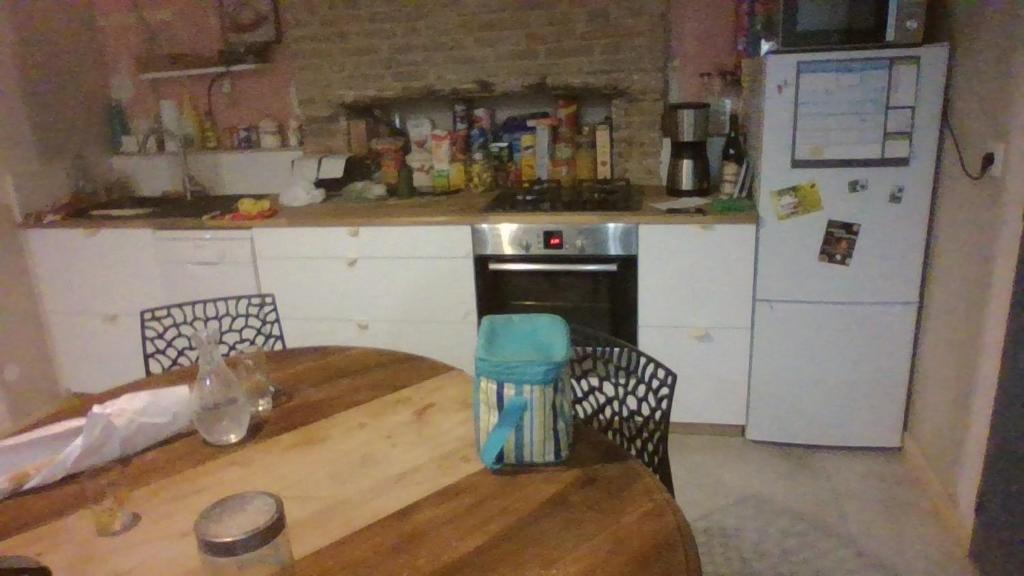 cocina con mesa de madera y nevera en Chambre dans maison, en Betton