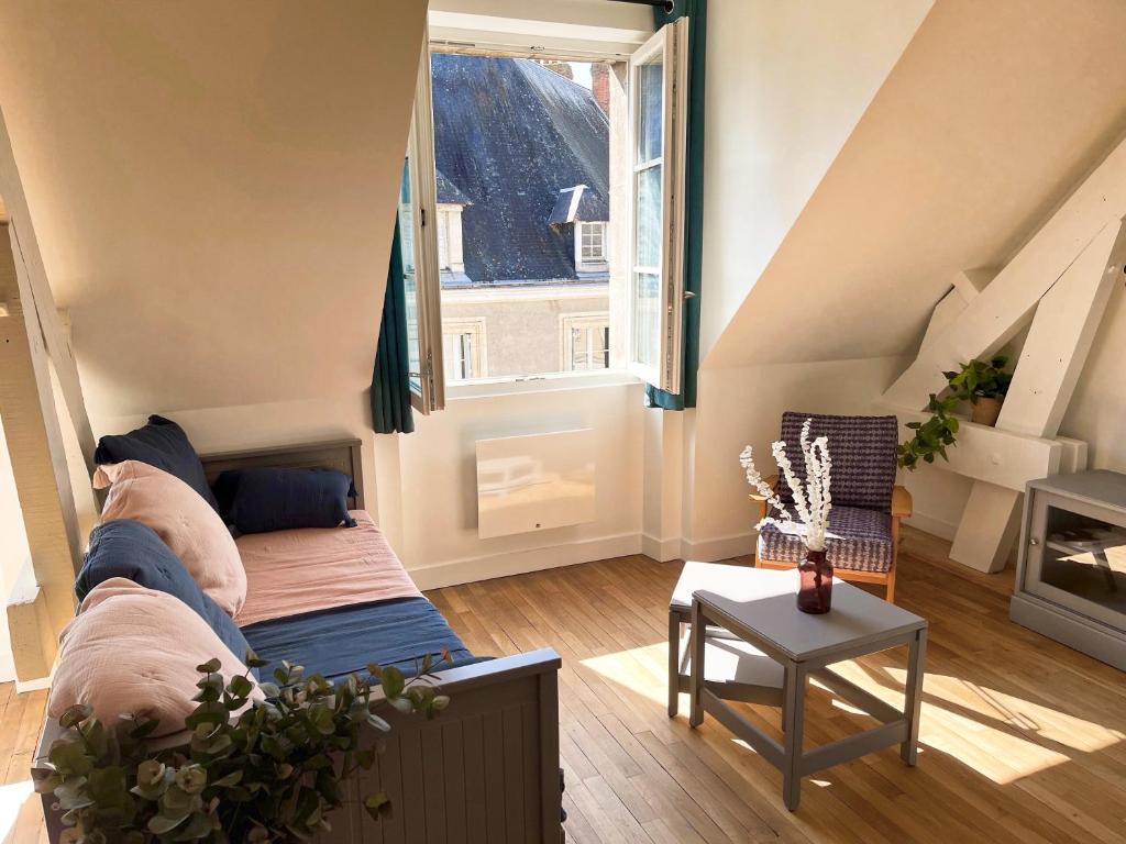 een woonkamer met een bank en een groot raam bij Appartement duplex rénové vue sur la Loire in Blois