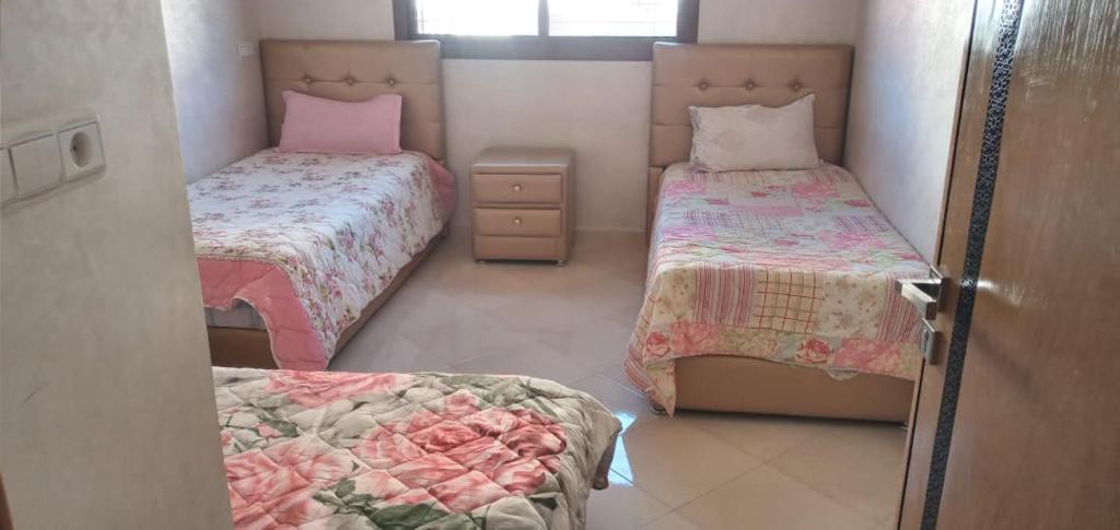 Habitación pequeña con 2 camas y ventana en Dar fatima, en Temara
