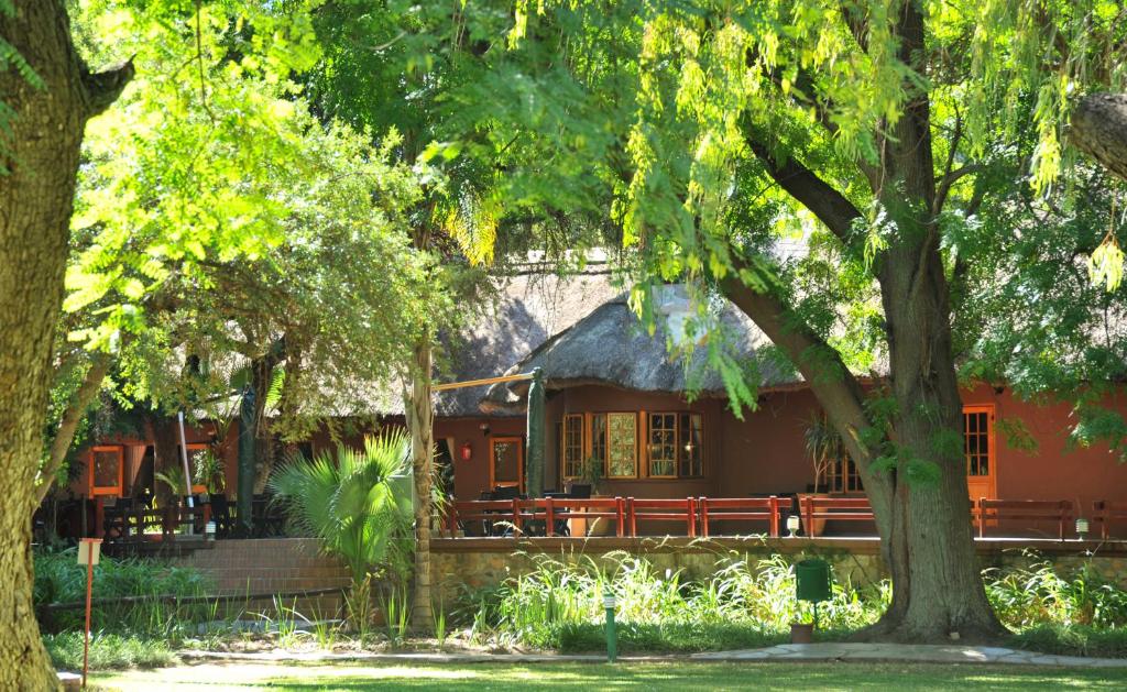 un edificio con un banco en un parque con árboles en Cresta Marang Gardens Hotel, en Francistown