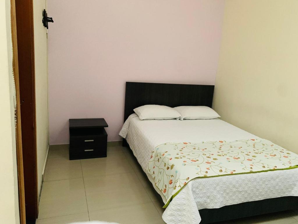 Habitación pequeña con cama y mesita de noche en Hostal Zaguán Caldense, en Manizales