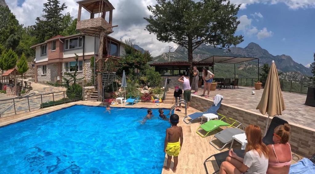 a group of people standing around a swimming pool at Gökdere Evleri in Antalya