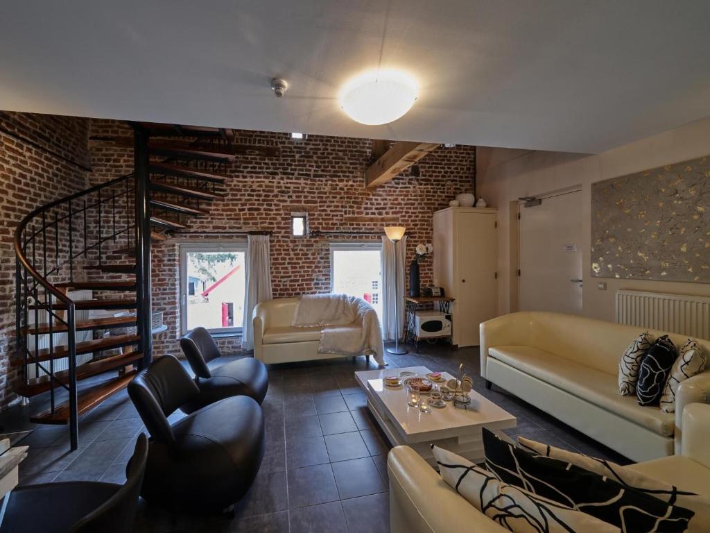 uma sala de estar com mobiliário de couro e uma parede de tijolos em Simplistic Villa in Mesch with Garden em Withuis