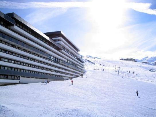 a group of people skiing in the snow in front of a building at Appartement duplex aux Ménuires 4 personnes in Les Menuires