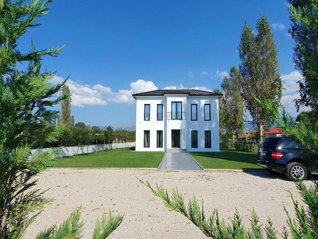 een auto geparkeerd voor een wit huis bij Nerium Garden Inn Tirana Airport in Rinas